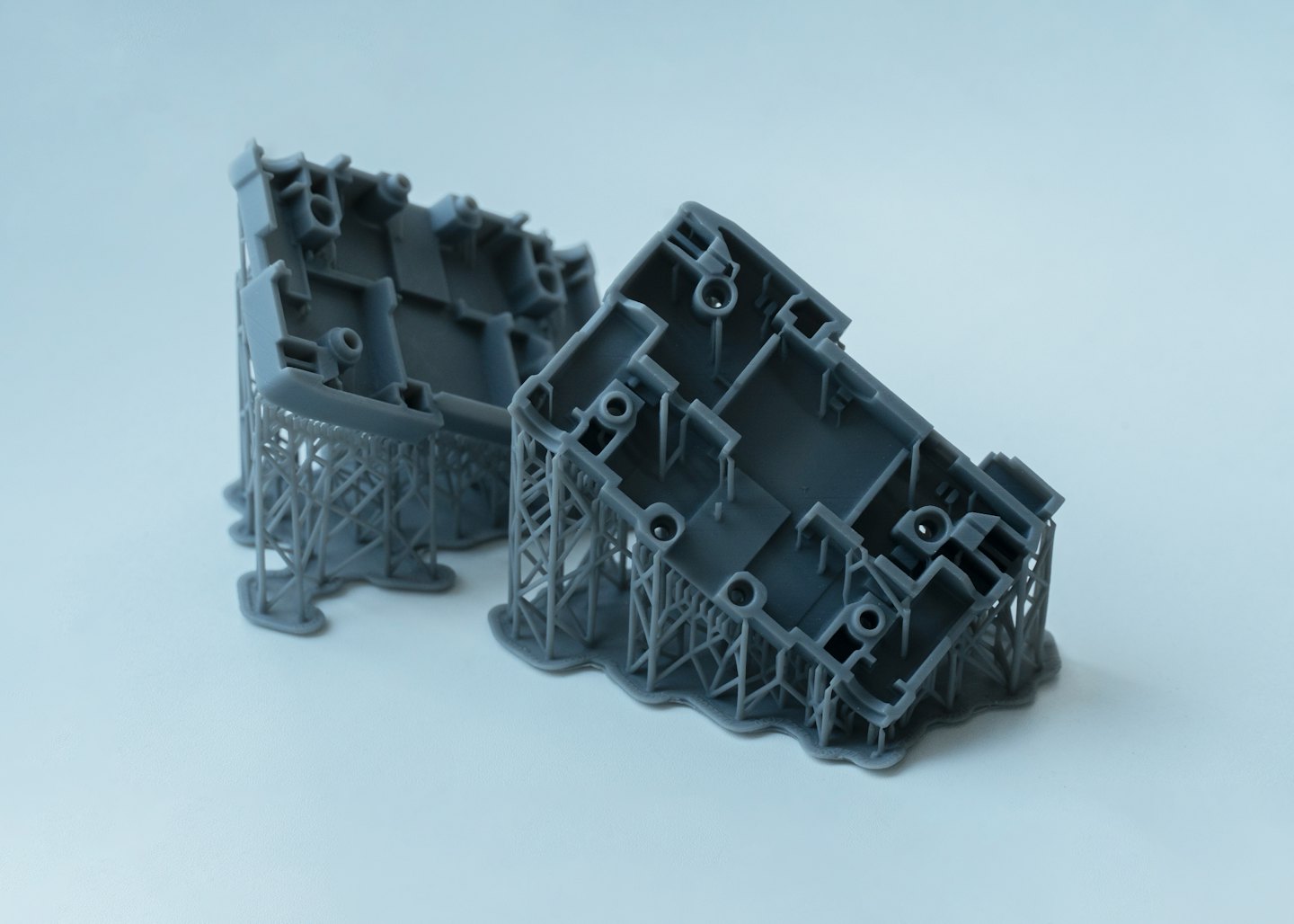 Dva sivé 3D vytlačené živicové prototypy s podporami.