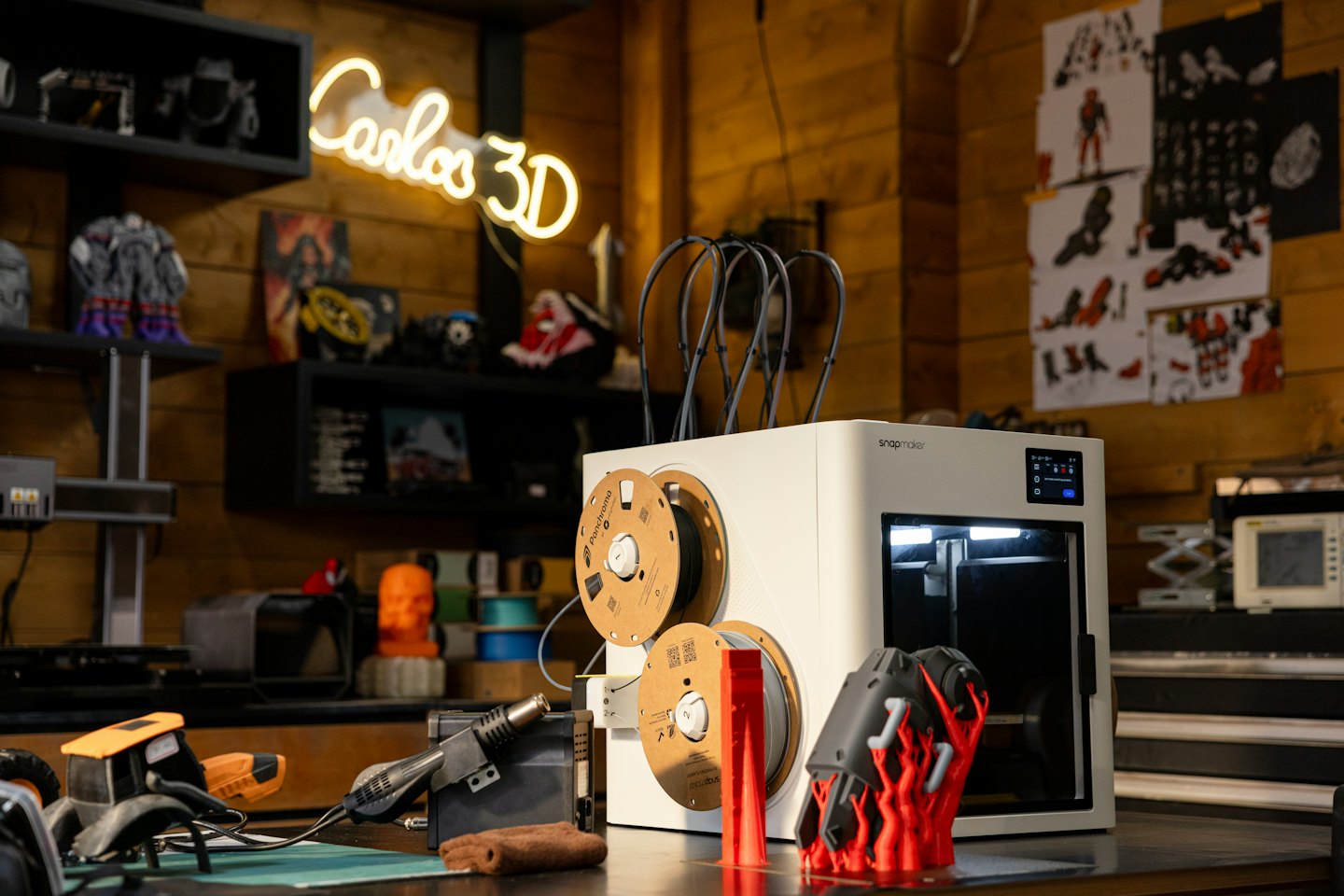 Moderná 3D tlačiareň vytvára na pracovnom stole červený objekt.